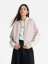 a lady in pink varsity jacket with black skirt